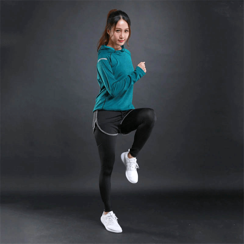 Woman wearing sports hoodie and leggings, showcasing gym fitness style with reflective print, in action pose on dark background.